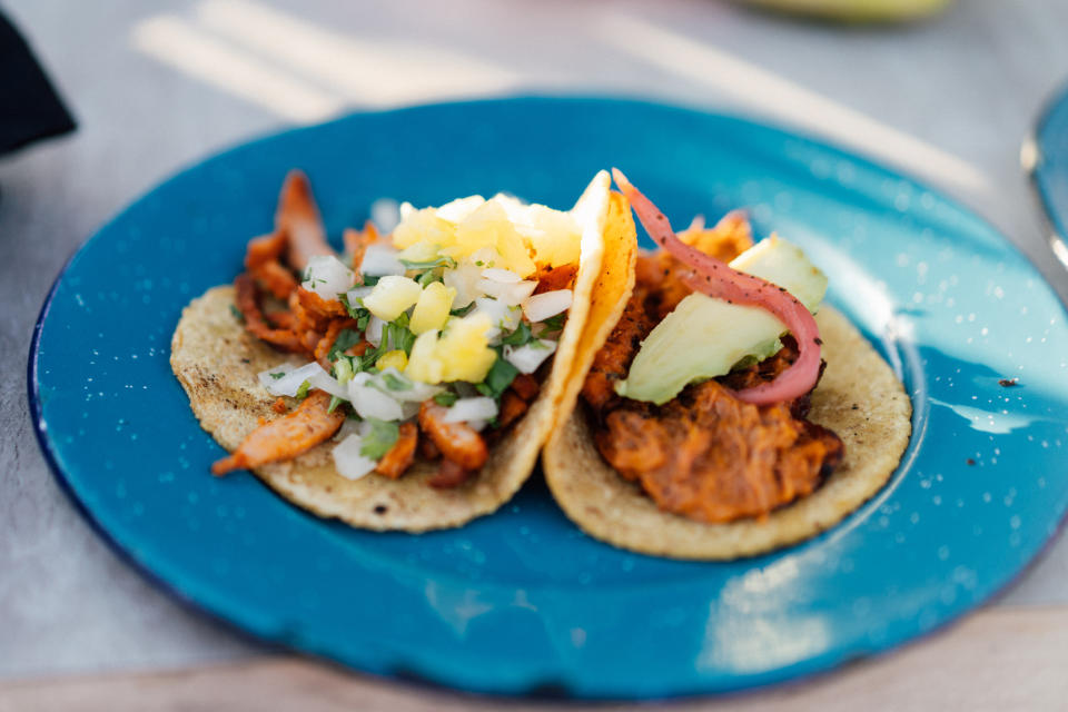 Two tacos with assorted toppings on a blue plate