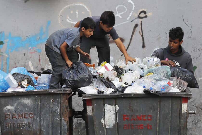 FILE - Boys scavenge in a dumpster for valuables and metal cans that can be resold, in Beirut, Lebanon, June 17, 2021. As Lebanon faces one of the world's worst financial crises in modern history, now even its trash has become a commodity fought over in the street. (AP Photo/Hussein Malla, File)