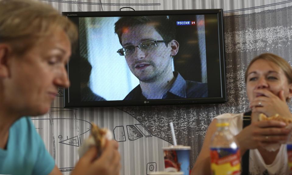 Transit passengers eat at a cafe with a TV screen with a news program showing a report on Edward Snowden, in the background, at Sheremetyevo airport in Moscow Wednesday, June 26, 2013. Russia’s President Vladimir Putin said Tuesday that National Security Agency leaker Edward Snowden has remained in Sheremetyevo’s transit zone, but media that descended on the airport in the search for him couldn’t locate him there. (AP Photo/Sergei Grits)