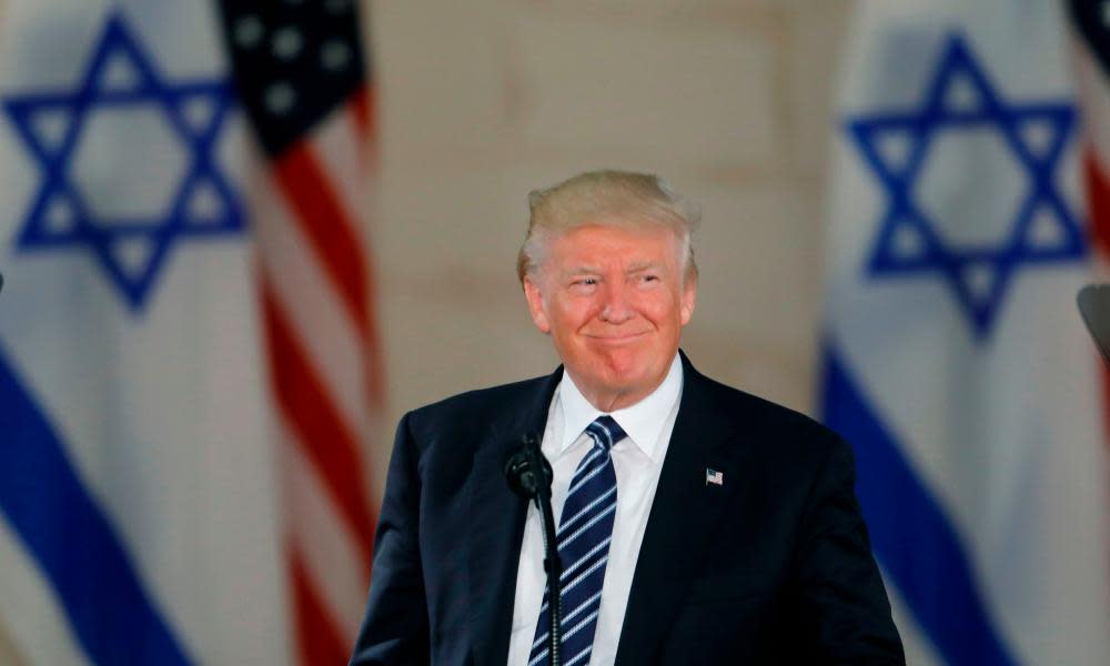 Donald Trump standing in front of Israeli and US flags.