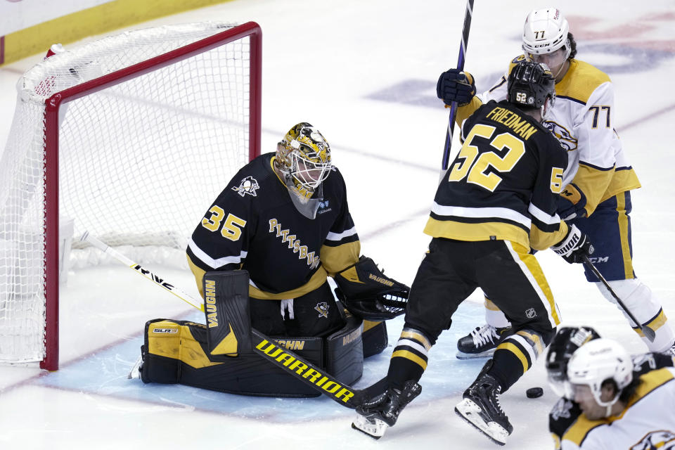 Pittsburgh Penguins goaltender Tristan Jarry (35) stops a shot as Mark Friedman (52) defends against Nashville Predators' Luke Evangelista (77) during the first period of an NHL hockey game in Pittsburgh, Thursday, March 30, 2023. (AP Photo/Gene J. Puskar)