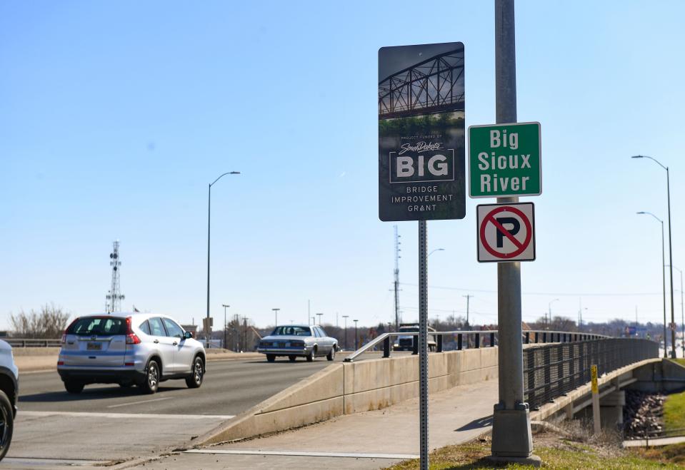 Cars drive on the 12th Street bridge over the Big Sioux River, past a sign indicating the bridge has been improved by the Bridge Improvement Grant on Thursday, April 21, 2022, in Sioux Falls.