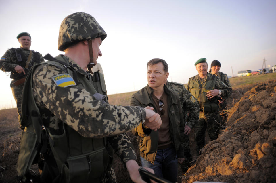 In this photo taken on Monday, March 24, 2014, Oleh Lyashko, center, a lawmaker, who supported the protests that ousted Russian-leaning president Viktor Yanukovych and his government, shakes hands with a soldier while visiting Ukrainian troops near Crimea, annexed by Russia, to support the Ukrainian soldiers’ spirit. Ukraine's government ordered Ukrainian troops to pull back Monday from Crimea, ending days of wavering as Russian forces stormed and seized bases on the peninsula.(AP Photo/Osman Karimov)