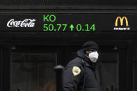 A security guard walks by a stock ticker displaying the cost of Coca-Cola shares at the New York Stock Exchange, Tuesday, Feb. 23, 2021. (AP Photo/Mark Lennihan)