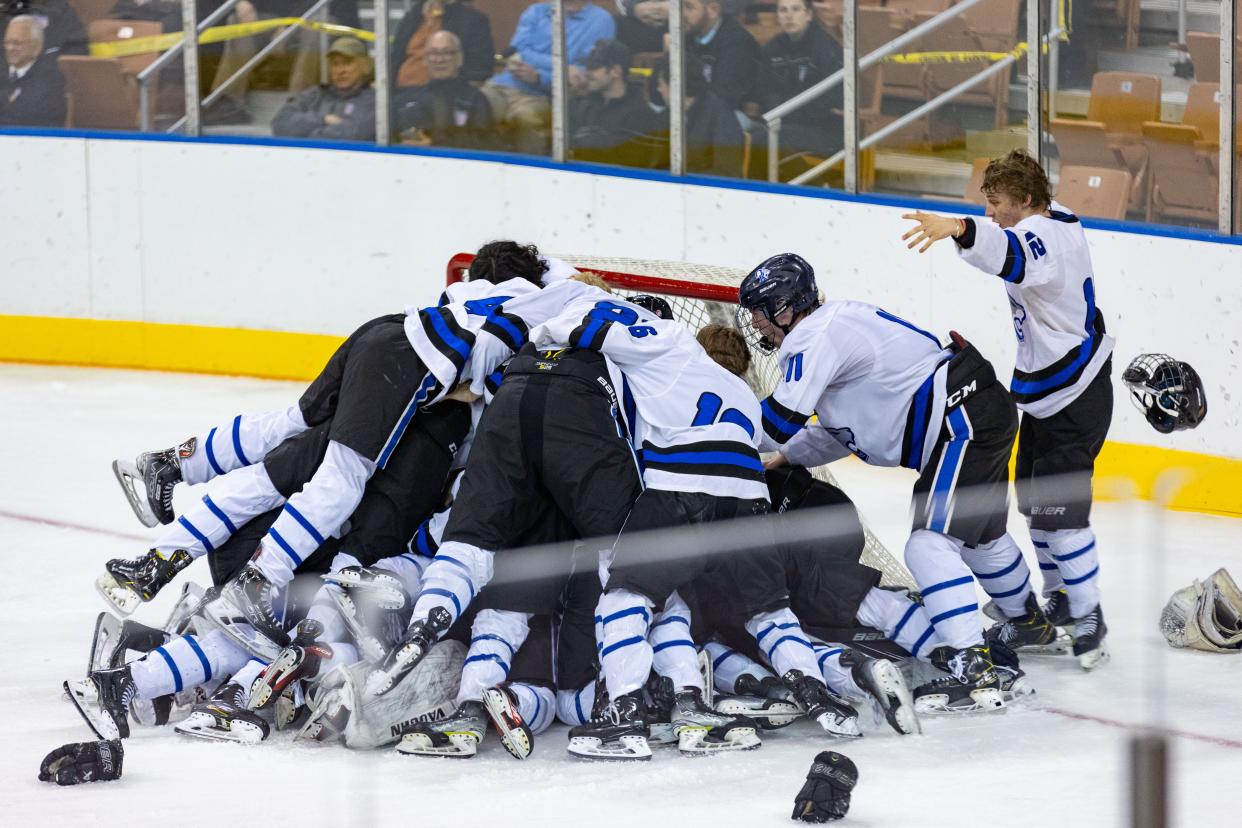 Members of the Oyster River High School boys hockey team leap on goalie Cole Harwood after Saturday's 3-0 win over Spaulding in the Division II state championship game at Southern New Hampshire University Arena in Manchester.