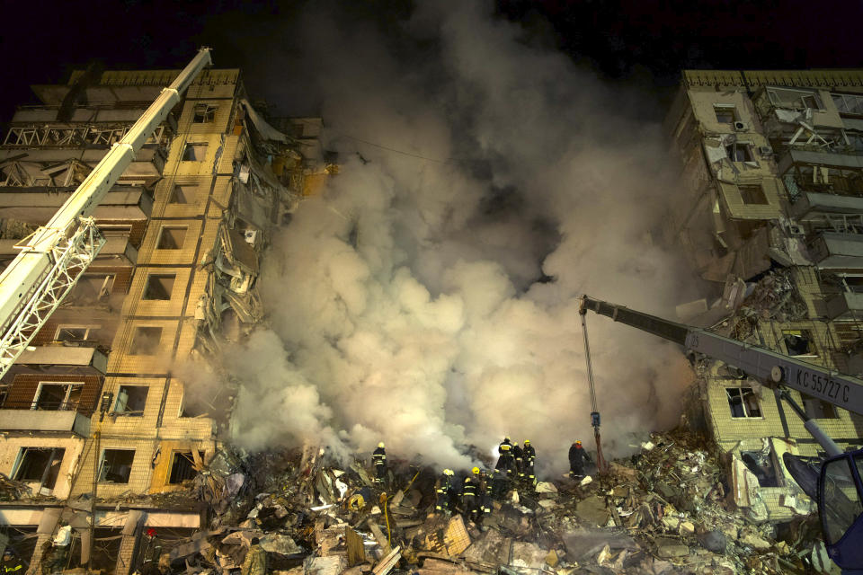 Emergency workers clear the rubble after a Russian rocket hit a multistory building leaving many people under debris in the southeastern city of Dnipro, Ukraine, Saturday, Jan. 14, 2023. (AP Photo/Evgeniy Maloletka)