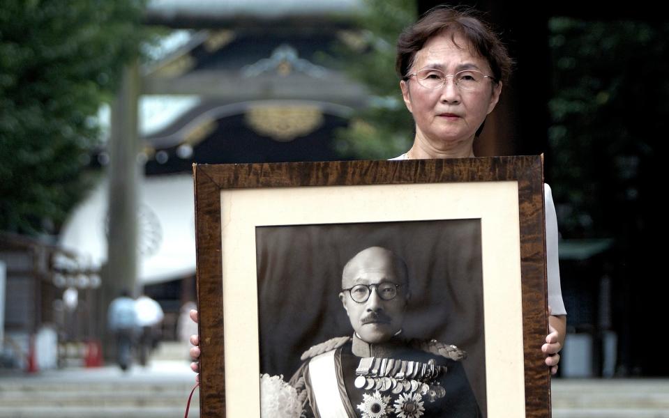 Yuko Tojo, granddaughter of Japan's wartime leader, General Hideki Tojo, poses with a photo of her grandfather outside Yaskuni Shrine in Tokyo - Robert Gilhooly