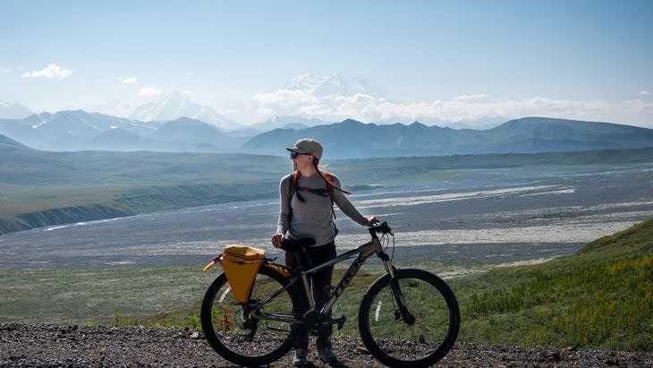 a woman with a bike and a beautiful landscape