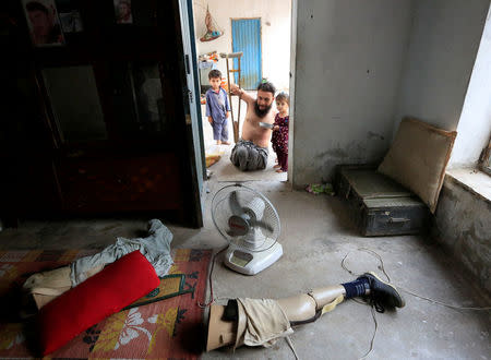 Khushhal Khan Ayobi 34, disable Afghan National Army (ANA) soldier walks with his children at his house in Jalalabad province, Afghanistan. August 2, 2017. REUTERS/Parwiz