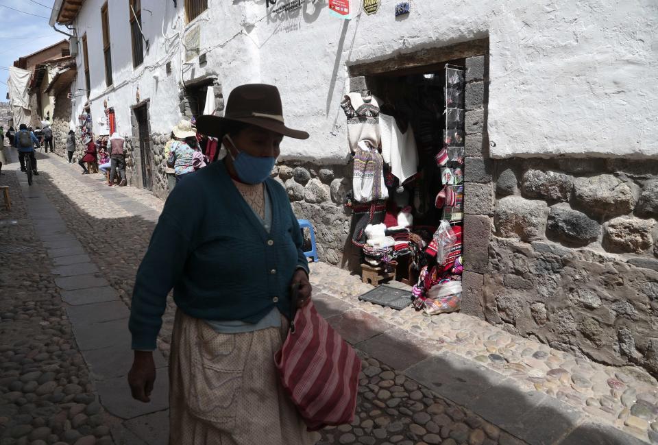 Una mujer pasa frente a las tiendas en una calle desprovista de turistas en medio de la pandemia de COVID-19 en Cusco, Perú, el jueves 29 de octubre de 2020. Todos los sitios importantes alrededor de Cusco --la capital de los Incas-- están abiertos actualmente de forma gratuita con la esperanza de generar turismo después que el encerramiento por el coronavirus paralizó su actividad y le ocasionara la peor crisis de su historia reciente. (Foto AP/Martín Mejía)