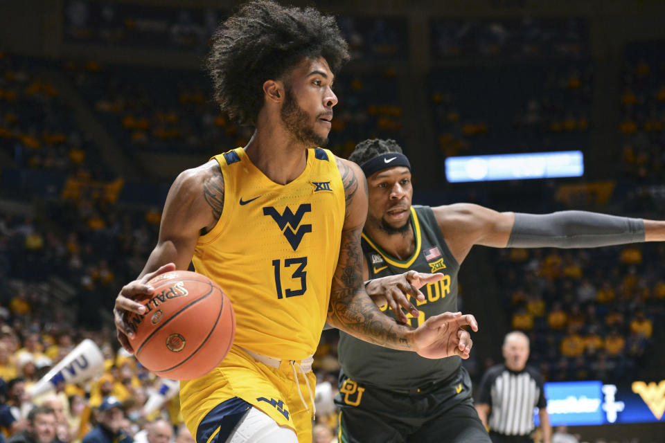 West Virginia forward Isaiah Cottrell (13) drives to the basket while being guarded by Baylor forward Flo Thamba (0) during the first half of an NCAA college basketball game in Morgantown, W.Va., Tuesday, Jan. 18, 2022. (William Wotring)