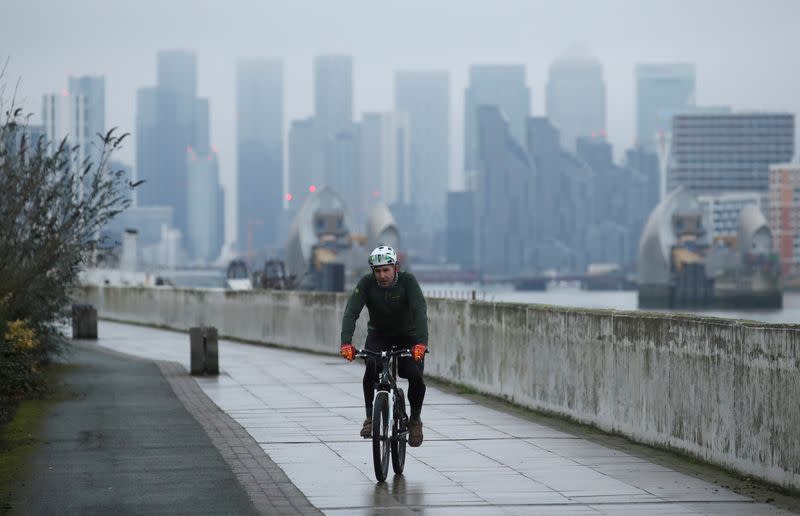 FILE PHOTO: FILE PHOTO: Buildings are seen in the Canary Wharf business district, as a man cycles along a path, amid the outbreak of the coronavirus disease (COVID-19), in London