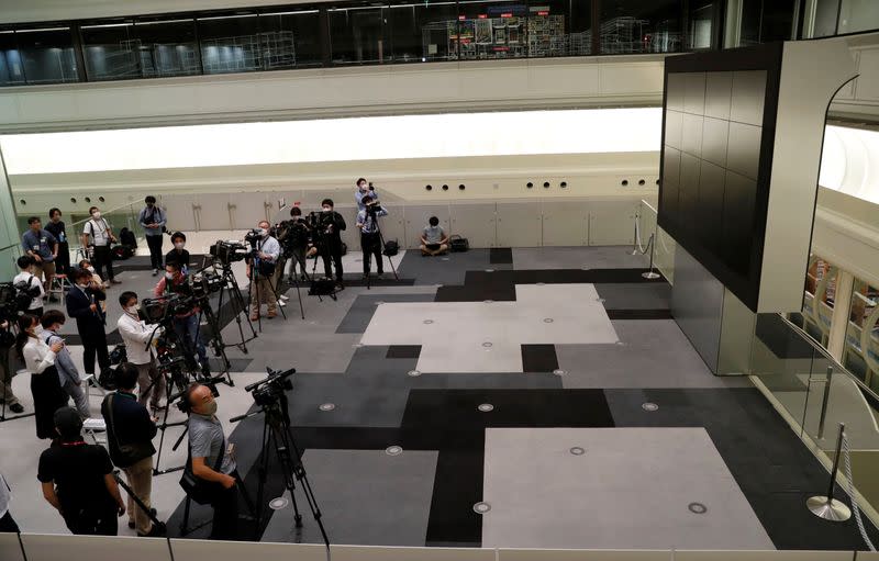 TV camera man wait for the opening of market in front of a large screen showing stock prices at the Tokyo Stock Exchange in Tokyo