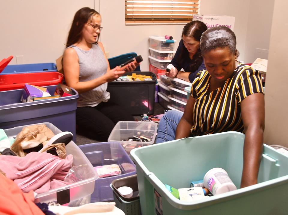 New Life Mission residents Tiffany, Brittany and Jelema sort and organize a roomful of donated health and beauty items at the former Hacienda Girls Ranch in Melbourne.