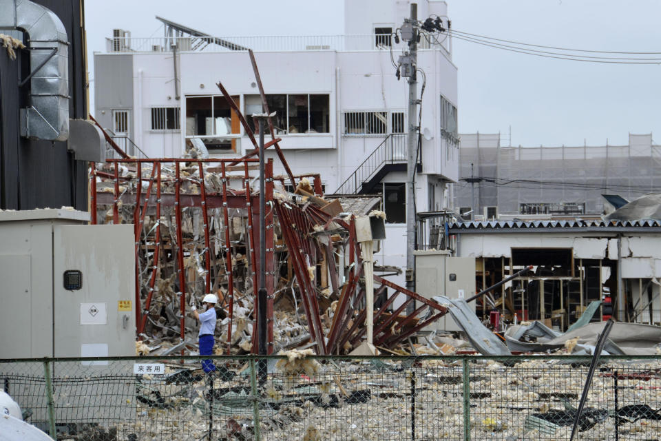 An investigator stands in front of a damaged building following an explosion in Koriyama, Fukushima prefecture, northern Japan Thursday, July 30, 2020. At least more than a dozen people were injured and being taken to hospitals after a sudden explosion blew off walls, windows and debris in the neighborhood. (Kyodo News via AP)