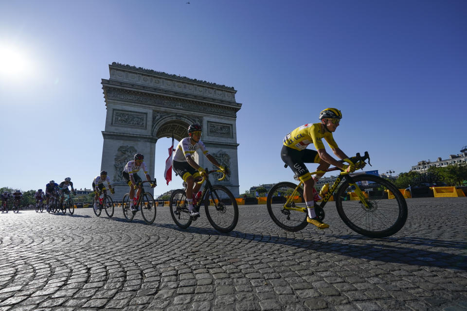 Slovenia's Tadej Pogacar, wearing the overall leader's yellow jersey, passes the Arc de Triomphe during the twenty-first and last stage of the Tour de France cycling race over 108.4 kilometers (67.4 miles) with start in Chatou and finish on the Champs Elysees in Paris, France,Sunday, July 18, 2021. (AP Photo/Daniel Cole)