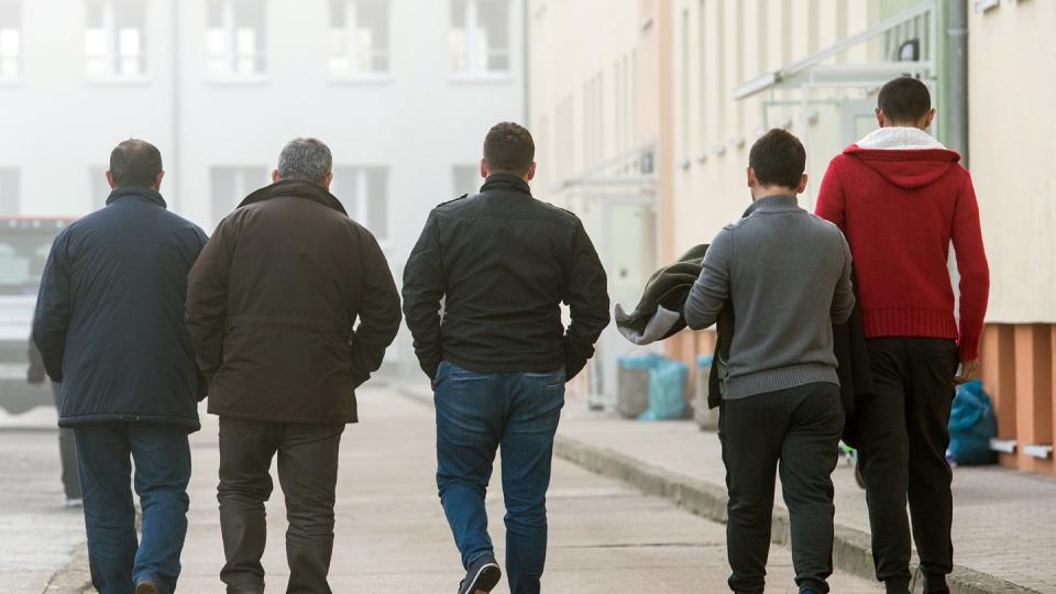 Asylbewerber gehen über das Gelände der Zentralen Ausländerbehörde in Eisenhüttenstadt. Seit dem 1. August können enge Angehörige wieder Anträge auf Familiennachzug stellen. Foto: Patrick Pleul/Archiv