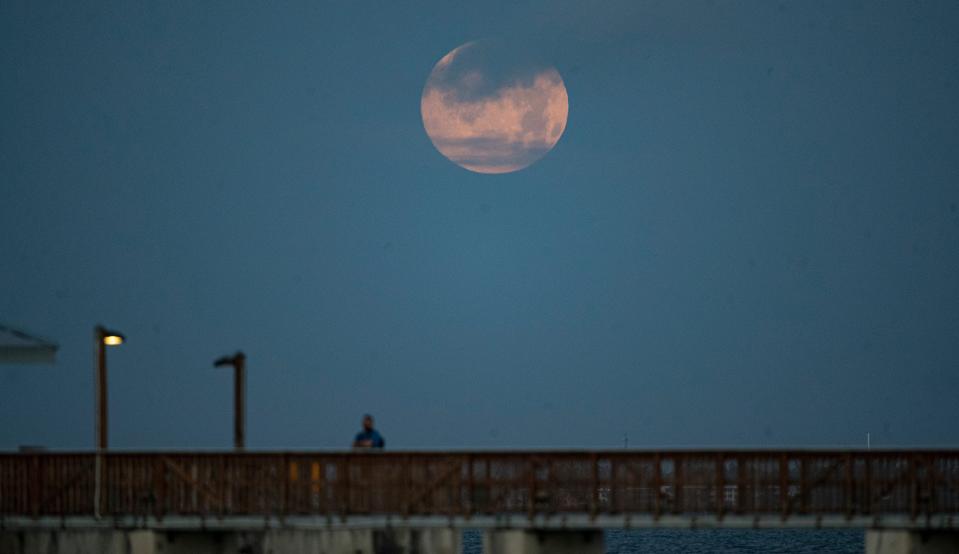 The so-called "pink moon" can be seen April 16, 2022 setting over the Fort Myers Beach pier.