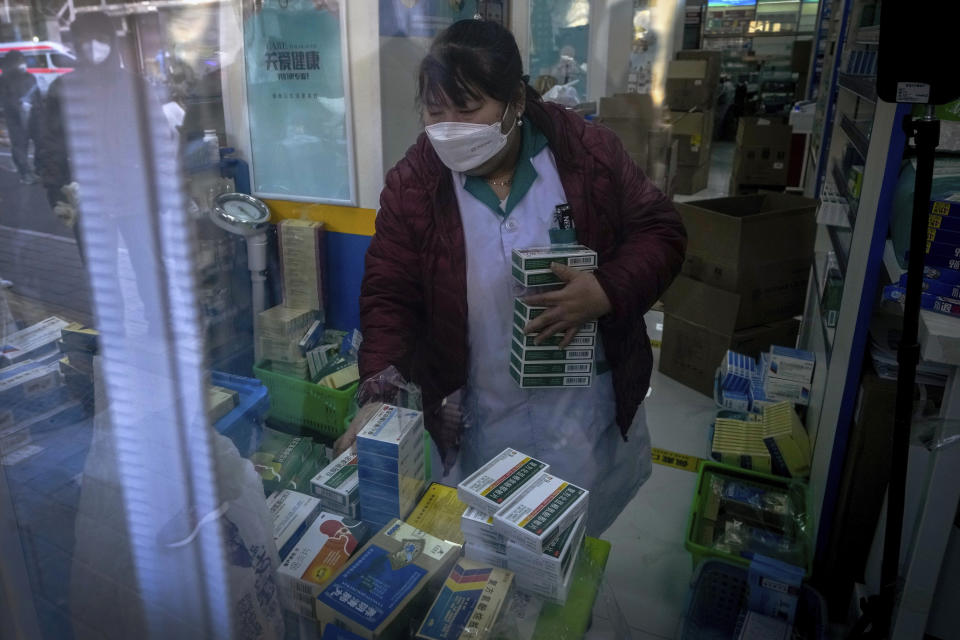 A masked worker prepares fever and cold medicine at a pharmacy in Beijing, Tuesday, Dec. 13, 2022. Some Chinese universities say they will allow students to finish the semester from home in hopes of reducing the potential of a bigger COVID-19 outbreak during the January Lunar New Year travel rush. (AP Photo/Andy Wong)