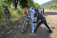 A man is frisked by police at a check point in El Estor in the northern coastal province of Izabal, Guatemala, Monday, Oct. 25, 2021. The Guatemalan government has declared a month-long, dawn-to-dusk curfew and banned pubic gatherings following protests against a nickel mining project. (AP Photo/Moises Castillo)