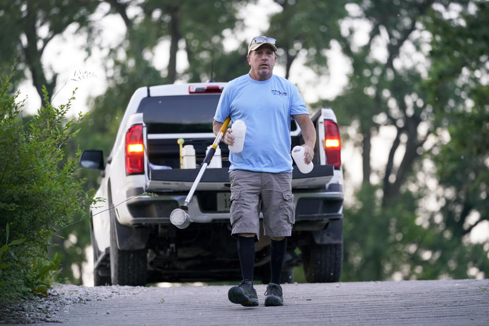 Des Moines Water Works employee Bill Blubaugh makes his way to collect a water sample from the Raccoon River, Thursday, June 3, 2021, in Des Moines, Iowa. Each day the utility analyzes samples from the Raccoon River and others from the nearby Des Moines River as it works to deliver drinking water to more than 500,000 people in Iowa's capital city and its suburbs. (AP Photo/Charlie Neibergall)