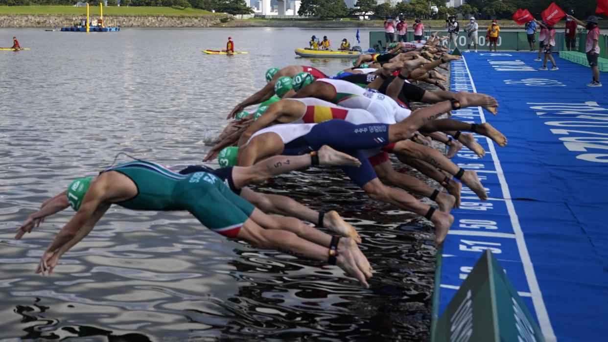 Athletes dive into the water for the start of the men's individual triathlon at the 2020 Summer Olympics, Monday, July 26, 2021, in Tokyo, Japan. (AP Photo/Jae C. Hong)