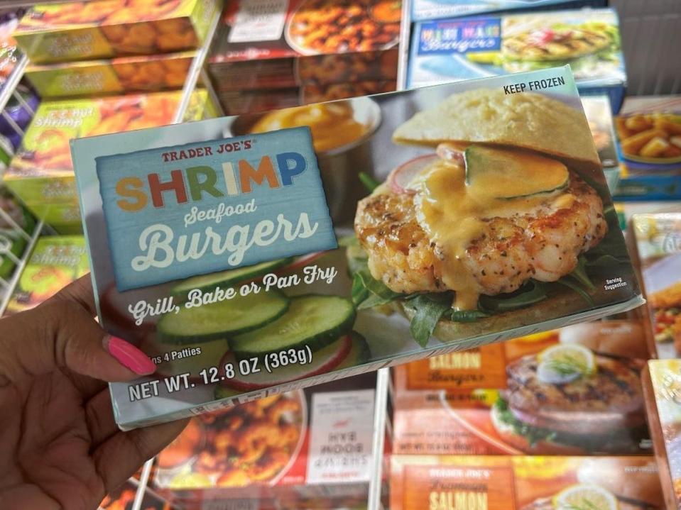 Woman holding a box of Trader Joe's shrimp burgers