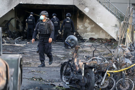 An Indonesian Special Forces Police counter-terrorism squad member walks by burned motorcycles following a blast at the Pentecost Church Central Surabaya (GPPS), in Surabaya, Indonesia May 13, 2018. REUTERS/Beawiharta