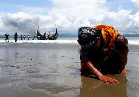 An exhausted Rohingya refugee woman touches the shore after crossing the Bangladesh-Myanmar border by boat through the Bay of Bengal, in Shah Porir Dwip, Bangladesh September 11, 2017. REUTERS/Danish Siddiqui
