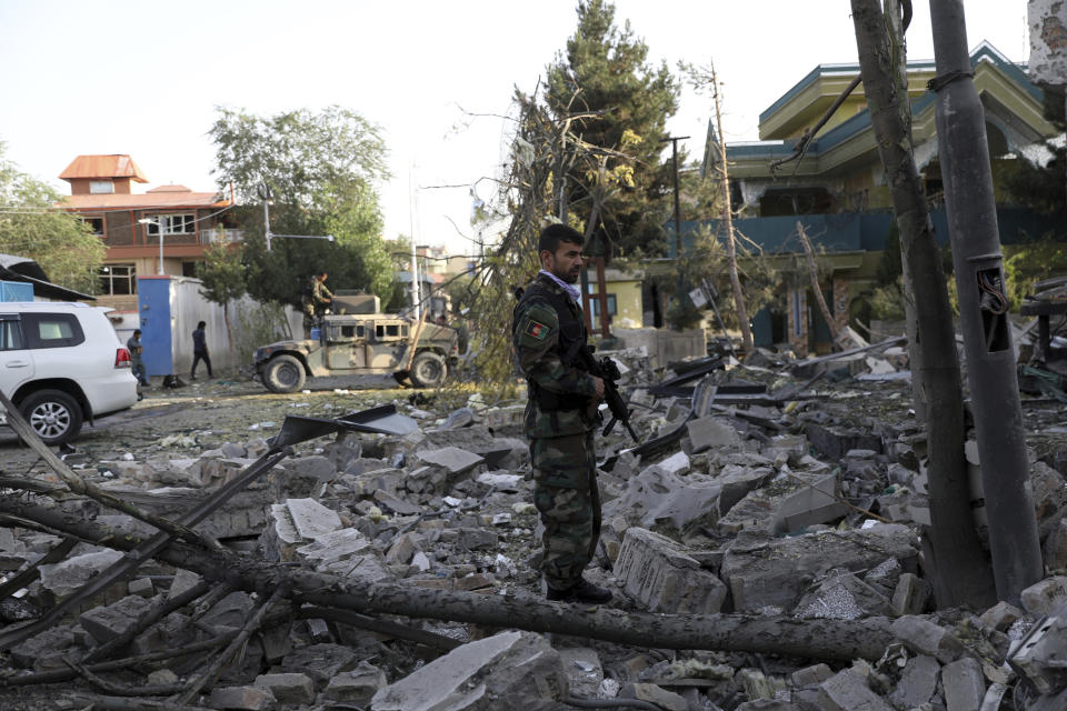 An Afghan security person stands amid debris from a damaged building following an attack in Kabul, Afghanistan, Wednesday, Aug. 4, 2021. A powerful explosion rocked an upscale neighborhood of Afghanistan's capital Tuesday in an attack that apparently targeted the country's acting defense minister. (AP Photo/Rahmat Gul)