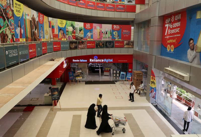 FILE PHOTO: Customers walk past a digital store of Reliance Industries Ltd, in Mumbai