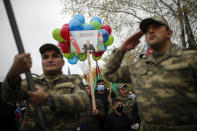 Azerbaijani soldiers and civilians hold a portrait of Azerbaijani President Ilham Aliyev and world reading "Karabakh is Azerbaijan!" as they celebrate the transfer of the Lachin region to Azerbaijan's control, as part of a peace deal that required Armenian forces to cede the Azerbaijani territories they held outside Nagorno-Karabakh, in Aghjabadi, Azerbaijan, Tuesday, Dec. 1, 2020. Azerbaijan has completed the return of territory ceded by Armenia under a Russia-brokered peace deal that ended six weeks of fierce fighting over Nagorno-Karabakh. Azerbaijani President Ilham Aliyev hailed the restoration of control over the Lachin region and other territories as a historic achievement. (AP Photo/Emrah Gurel