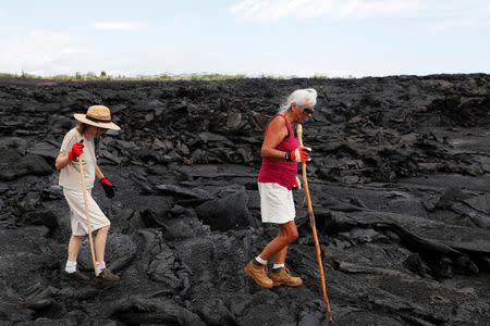 Diane Cohen, 64, (R) who was forced to leave her home when the Kilauea Volcano erupted and covered it with lava last summer, walks across her property with her friend, Sara Lau, in Kapoho, in Hawaii, U.S., April 1, 2019. Picture taken April 1, 2019. REUTERS/Terray Sylvester