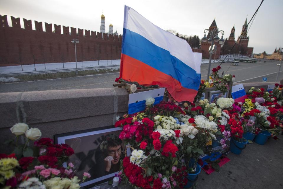 A portrait of Russian opposition leader Boris Nemtsov, a Russian national flag and flowers are laid at the place where he was gunned down, in Moscow, Russia, Sunday, Feb. 26, 2017. Thousands of Russians take to the streets of downtown Moscow to mark two years since Nemtsov was gunned down outside the Kremlin. (AP Photo/Ivan Sekretarev)