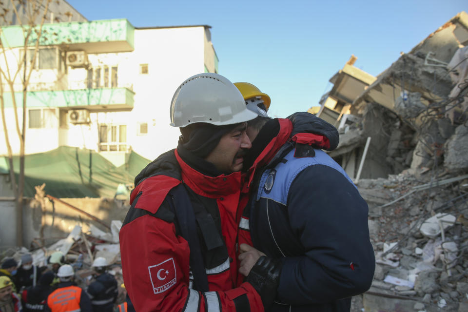 Rescuers weep by a collapsed building in Adiyaman, southern Turkey, Thursday, Feb. 9, 2023. Thousands who lost their homes in a catastrophic earthquake huddled around campfires and clamored for food and water in the bitter cold, three days after the temblor and series of aftershocks hit Turkey and Syria. ( AP Photo/Emrah Gurel)