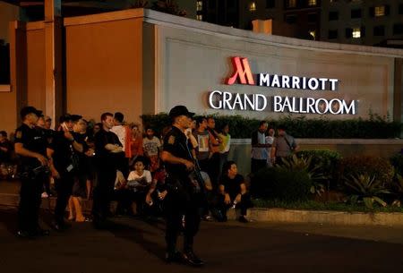 Policemen stand guard near evacuated employees of a hotel near a situation at a Resorts World building, in Pasay City, Metro Manila, Philippines June 2, 2017. REUTERS/Erik De Castro