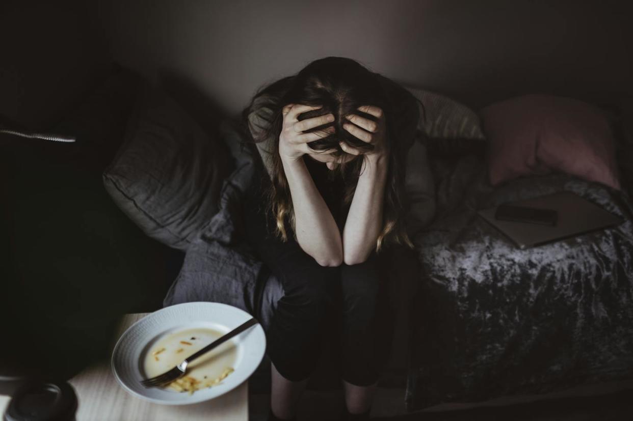 An increased disconnect from your body can make it easier to harm yourself, whether by disordered eating or suicide. <a href="https://www.gettyimages.com/detail/photo/high-angle-view-of-worried-woman-sitting-on-bed-royalty-free-image/1252672806" rel="nofollow noopener" target="_blank" data-ylk="slk:Maskot/Maskot via Getty Images;elm:context_link;itc:0;sec:content-canvas" class="link ">Maskot/Maskot via Getty Images</a>