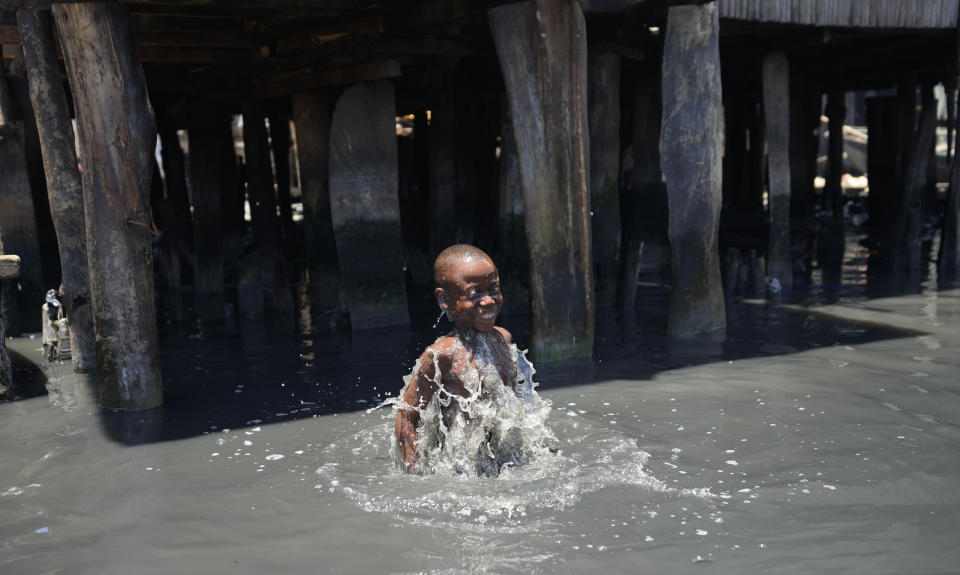 A child plays in filthy water surrounded by garbage in Nigeria's economic capital Lagos' floating slum of Makoko, Monday, March. 20, 2023. March 22 is World Water Day, established by the United Nations and marked annually since 1993 to raise awareness about access to clean water and sanitation. (AP Photo/Sunday Alamba)