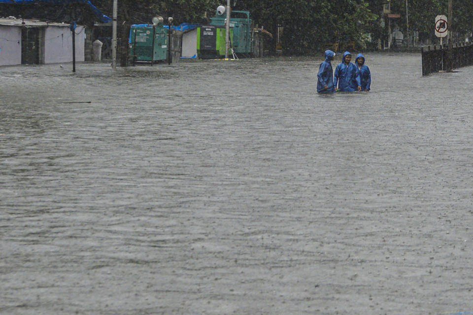 Commuters wade through a flooded road during a heavy monsoon rain in Mumbai on August 4, 2020. (Photo by INDRANIL MUKHERJEE/AFP via Getty Images)