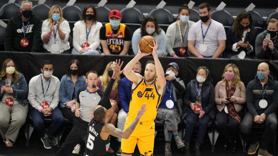 Utah Jazz forward Bojan Bogdanovic (44) shoots as San Antonio Spurs guard Dejounte Murray (5) defends while fans sit courtside in the first half during an NBA basketball game Monday, May 3, 2021, in Salt Lake City. (AP Photo/Rick Bowmer)