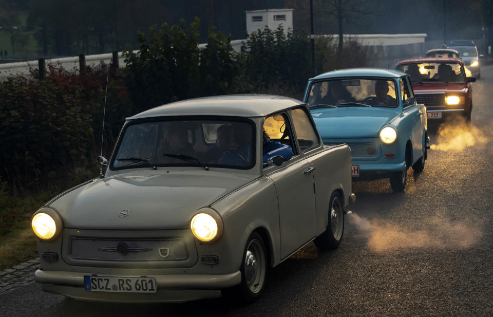 The legendary GDR Trabant (Trabi) cars drive along, during a symbolic wall opening, celebrating the 30th anniversary of the falling wall in the outdoor area of the German-German museum in Moedlareuth, Germany, Saturday, Nov. 9, 2019. Moedlareuth, named 'Little Berlin', was the symbol of a divided village along the borderline between East and West Germany. The border ran straight through the little village. (AP Photo/Jens Meyer)