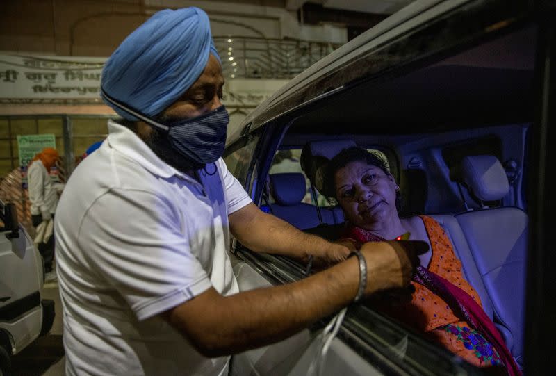 A volunteer uses an oximeter to check the oxygen level of a woman, in Ghaziabad