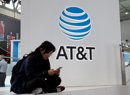 A woman looks at her mobile next to AT&T logo during the Mobile World Congress in Barcelona, Spain February 25, 2016. REUTERS/Albert Gea/File Photo
