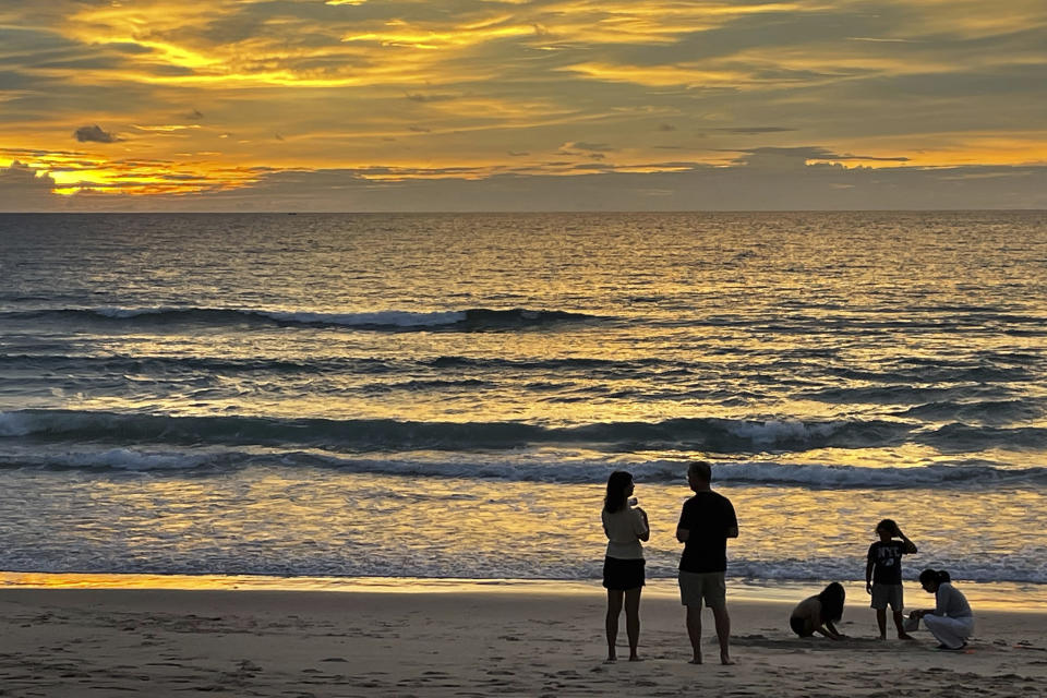 Tourists stand on Bang Tao Beach in Phuket, southern Thailand, Friday, Oct. 22, 2021. Thailand is accelerating plans to reopen the country to foreign tourists, slashing mandatory quarantines beginning Nov. 1 for fully-vaccinated COVID-19 visitors arriving by air from 46 countries and territories, officials announced Friday. (AP Photo/Patrick Quinn)