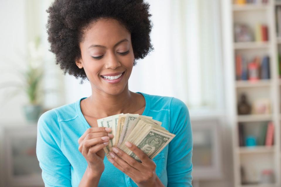 An investor smiles and counts money in a living room.