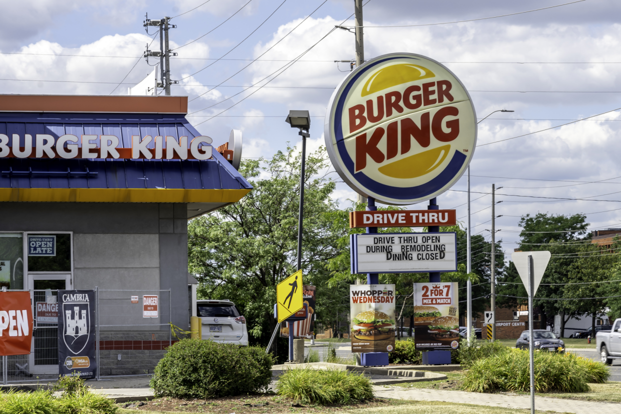 Exterior and sign of Burger King restaurant, Niagara Falls, Ontario, Canada with cars parked in the parking lot and a busy road to the right on a sunny summer day