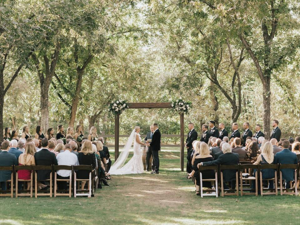 A bride and groom stand under an arch during their wedding ceremony.