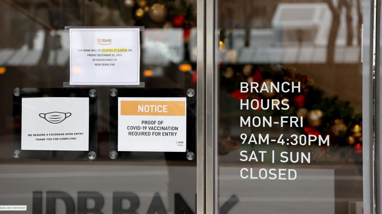 Signs outside an IDB Bank entrance in Manhattan, New York show a notice requiring anyone entering their branch to wear a mask and show proof of vaccination against COVID-19 last December 2021.
