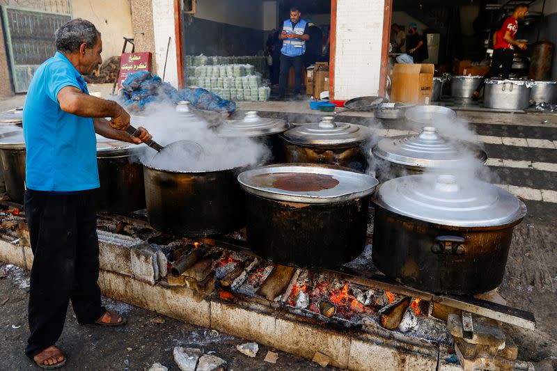 FILE PHOTO: Palestinians cook on firewood, amid fuel and cooking gas shortages, as the conflict between Israel and Hamas continues, in Khan Younis