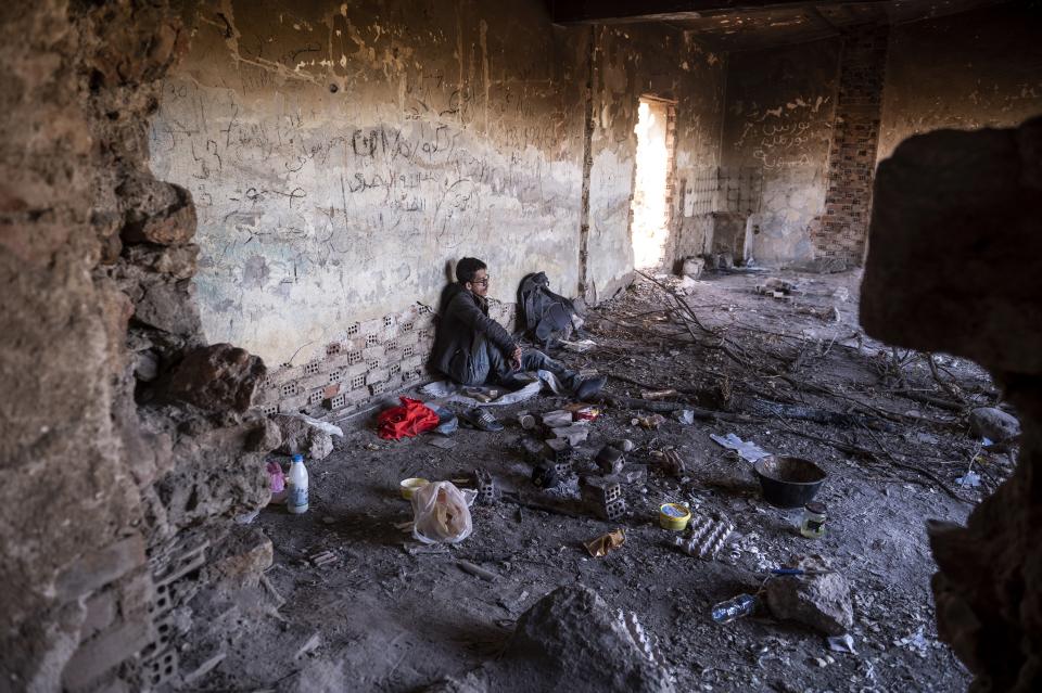 A Syrian man sits inside an abandoned army outpost near Ieropigi village, northern Greece, at the Greek - Albanian border, on Saturday, Sept. 25, 2021. A relatively smooth section of Greece's rugged border with Albania is turning into a major thoroughfare north for migrants in Greece seeking a better life in Europe's prosperous heartland. (AP Photo/Giannis Papanikos)